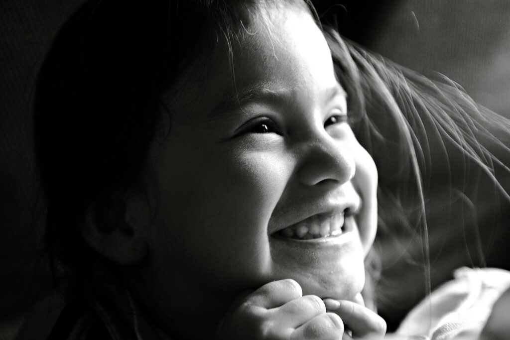 Delightful black and white portrait of a smiling child exhibiting pure joy and happiness.