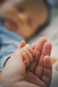 Baby's hand holding an adult's finger, symbolizing trust and care. Close-up view.