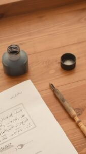 Elegant setup of traditional calligraphy tools including ink bottle, pen, and handwritten script on wooden table.