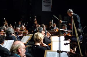 Maestro conducting an orchestra during a live concert in São Paulo, Brazil.
